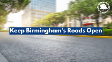 A blurred picture of an open road through a city centre. Text with a blue underlay reads, Keep Birmingham's roads open.